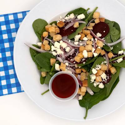 Spinach salad on a white plate with a blue checkered napkin